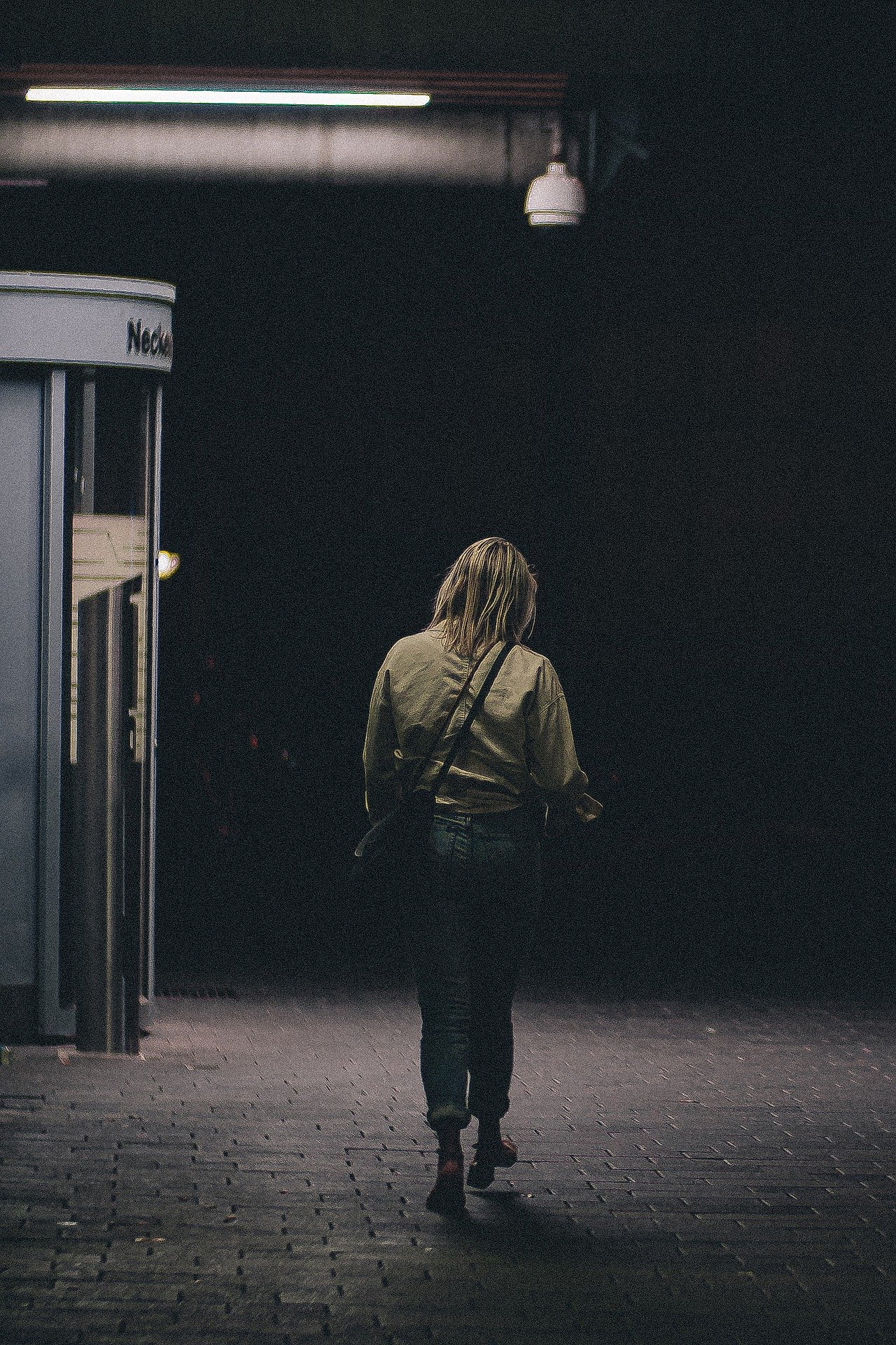 a woman walks down a street in the dark