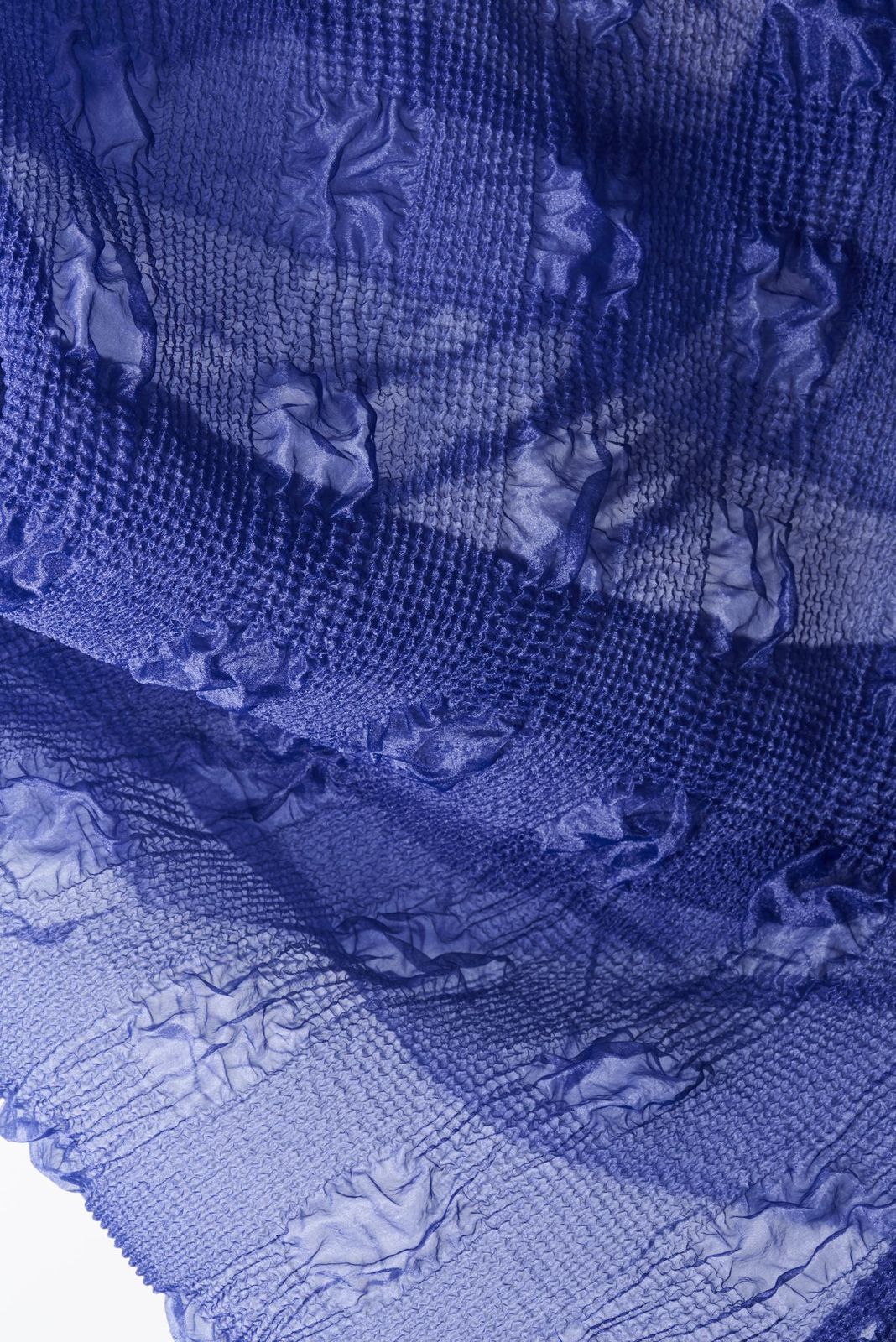 Blow up of a blue textile seen in transparency against a white background