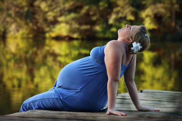 pregnant woman sits on wooden bench