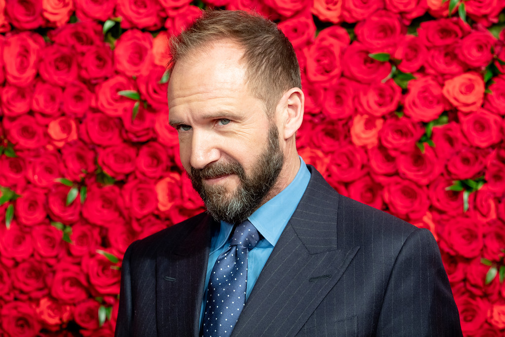ralph fiennes against a background of hot pink roses