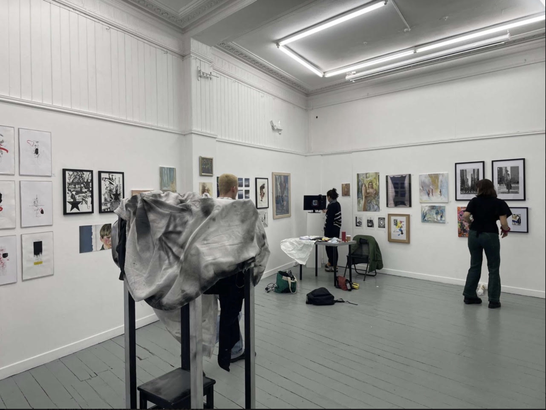 Studio space displaying the works of the Young Edinburgh Artists Exhibition. People walk through the space