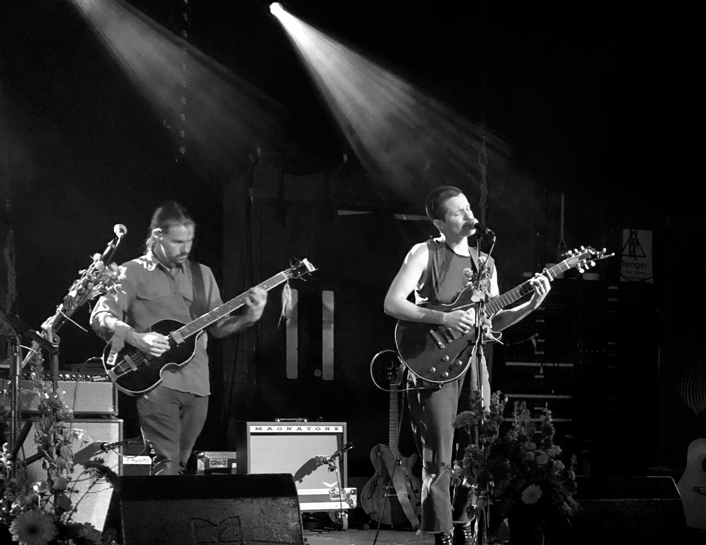 The band, Big Thief playing live onstage. Lead singer, Adrianne Lenker, is illuminated. The photo is in black and white