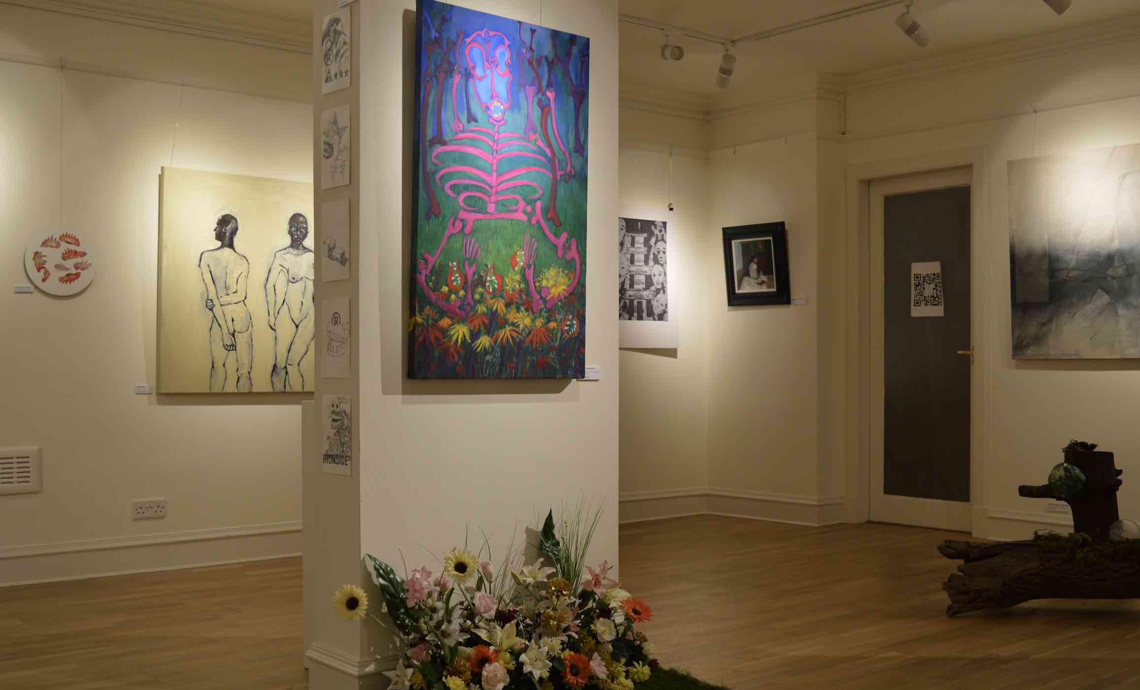 dimly lit Gallery,with spotlights on a column, and background walls covered with paintings, flowers on floor