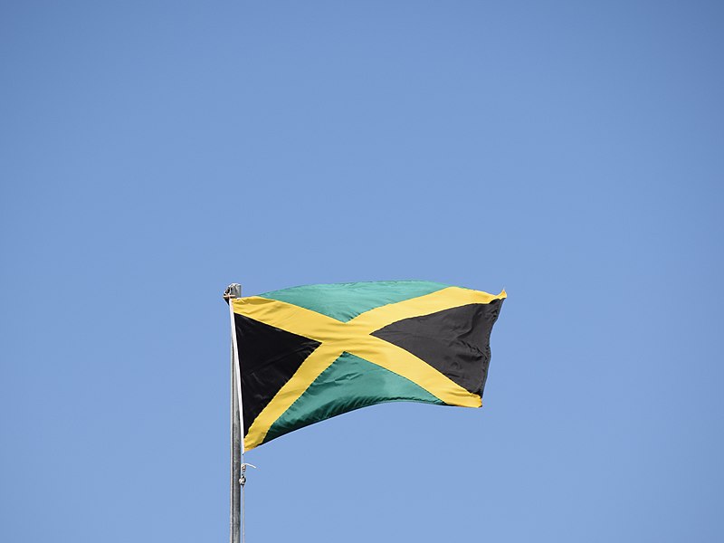 Jamaican flag is flying, background is a clear blue sky.
