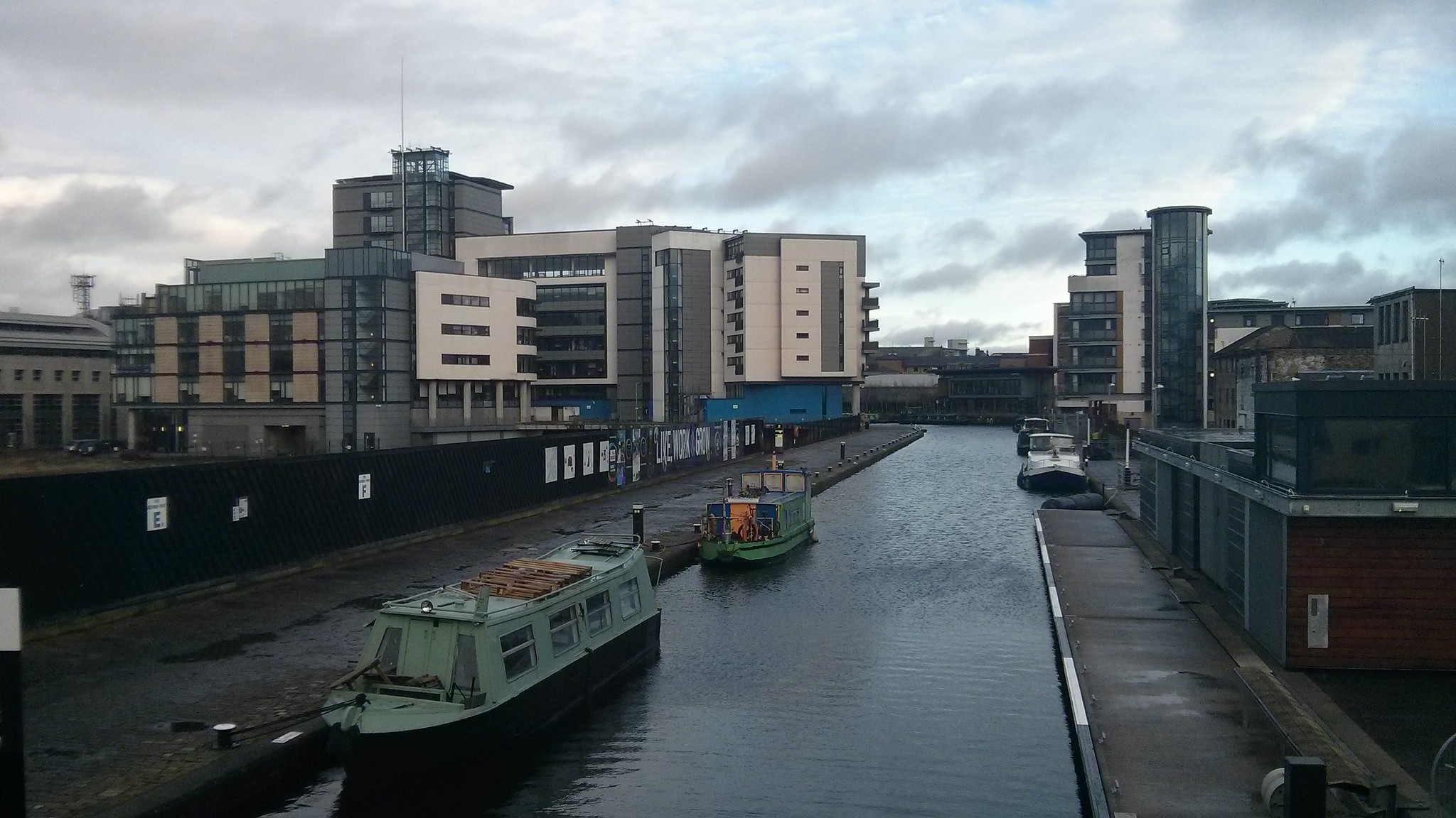 Several modern buildings stand around the end of a canal.