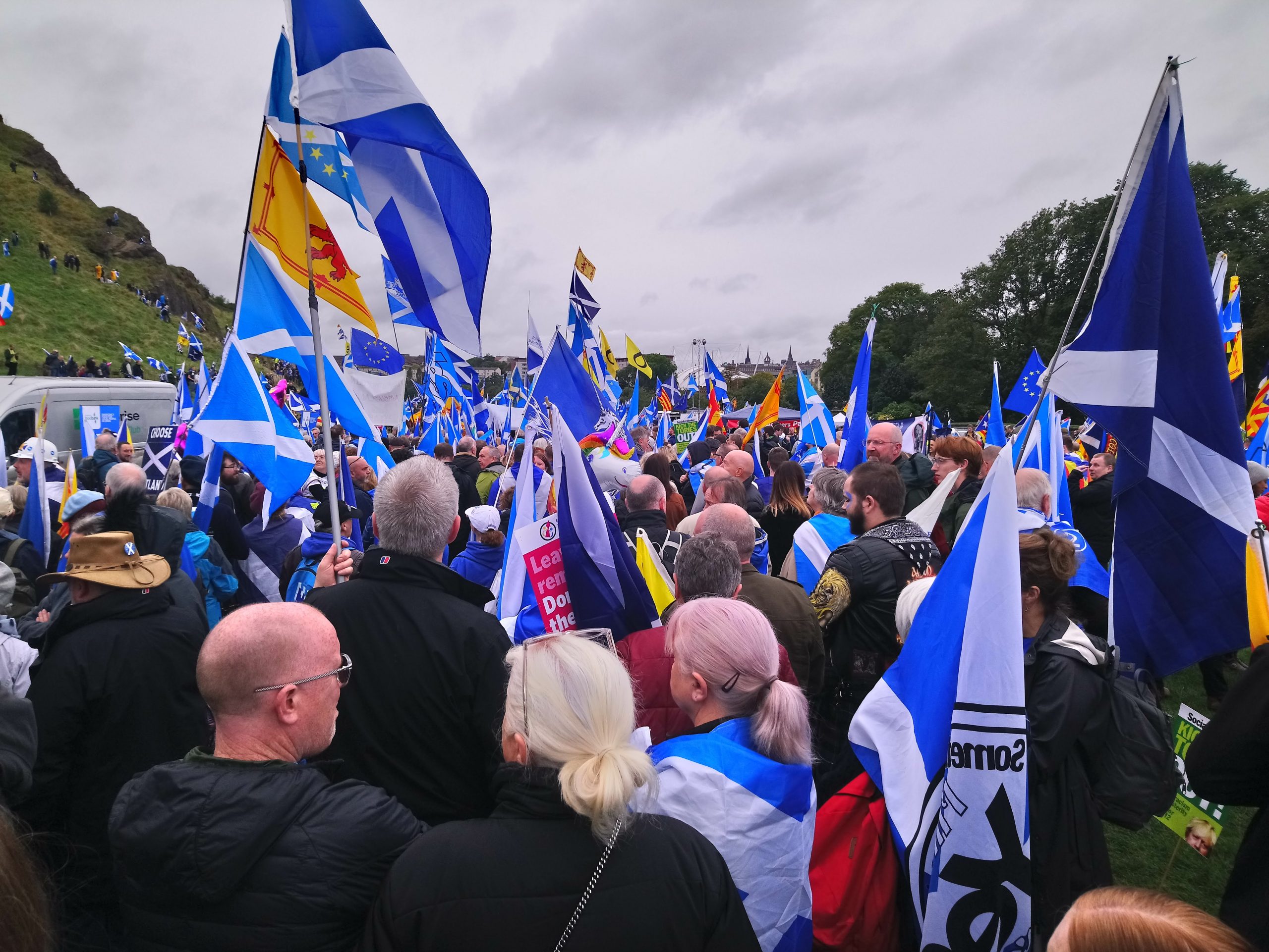 Edinburgh Independence March 2019, a crowd of people holding Scotland flags and marching in Holyrood