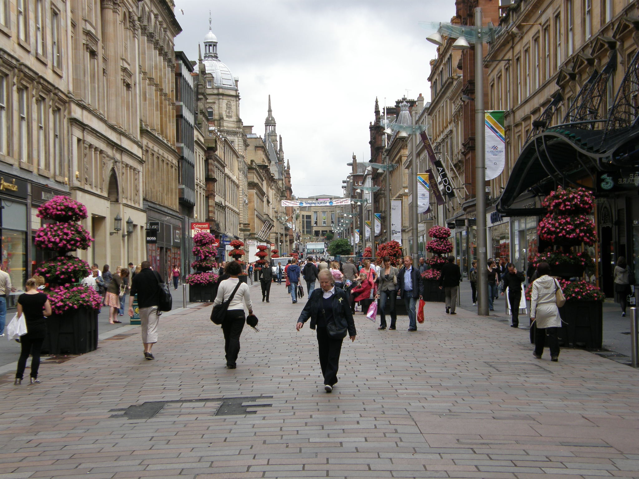 A pedestrianised street in Glasgow, paved with brick lined mostly with mid-19th century pedestrian buildings. The sky is gray, and the street environment is relatively hospitable.