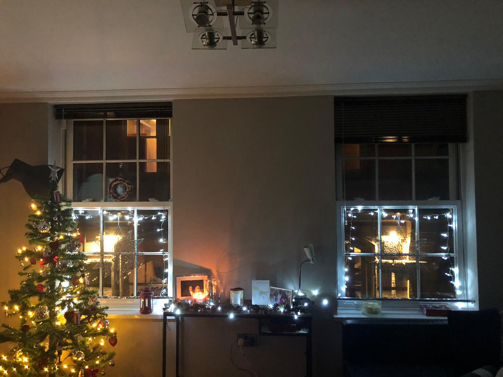 photo of a Christmas decorations in room with a christmas tree and fairy lights around the window
