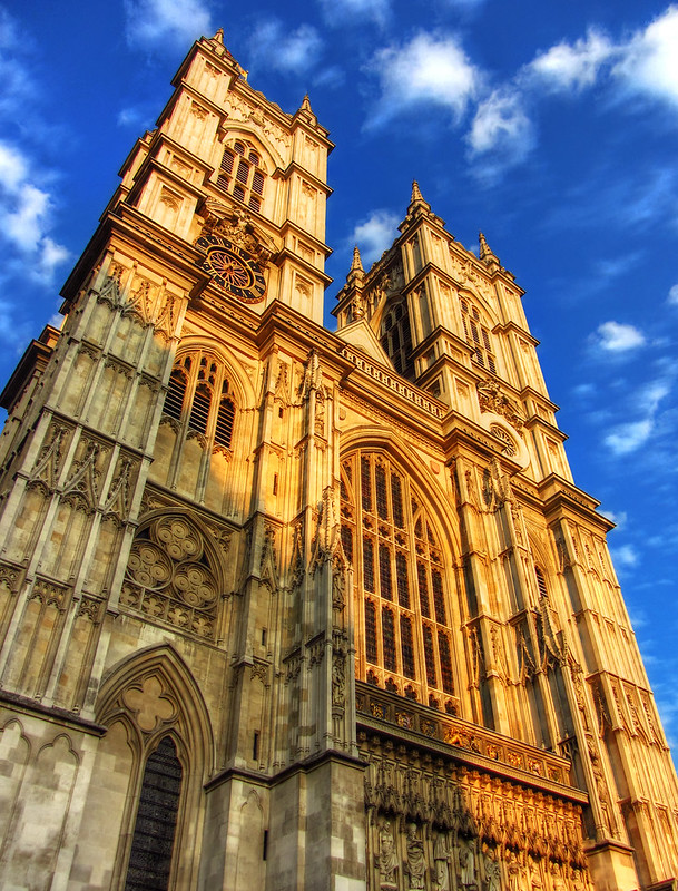 A view of Westminster Abbey from the front looking upwards, a partly cloudy sky behind