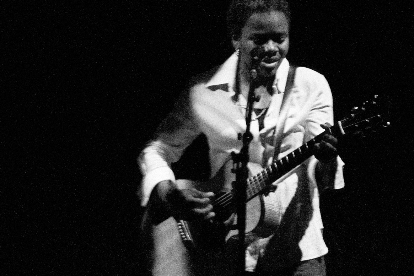 A black and white image of Tracy Chapman playing the guitar