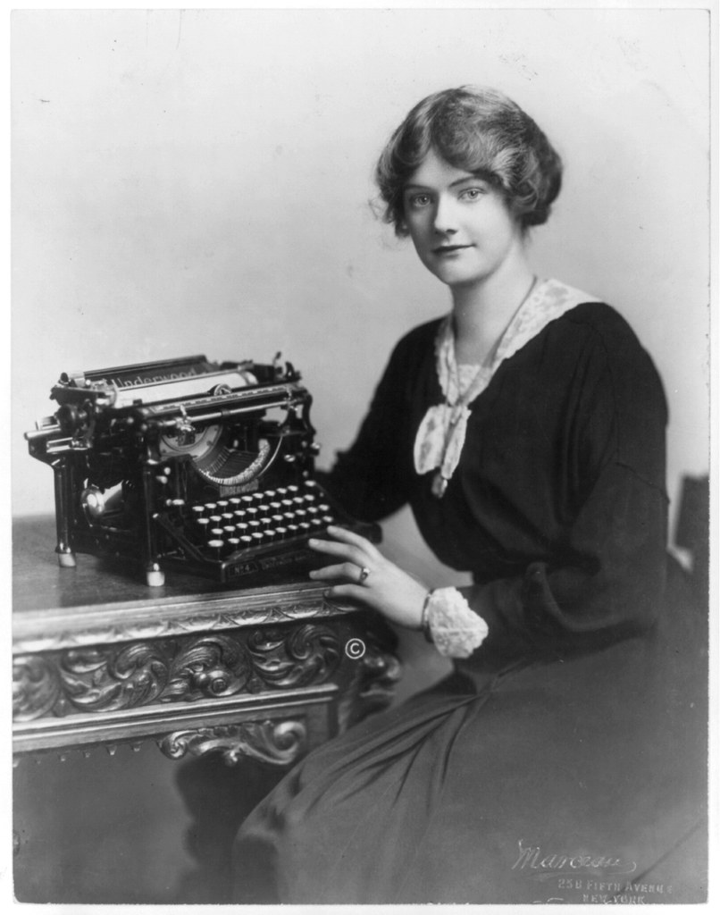 A black and white picture of a woman with a typewriter