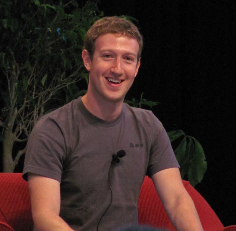 image of Zuckerberg wearing a dark top sat on a red sofa