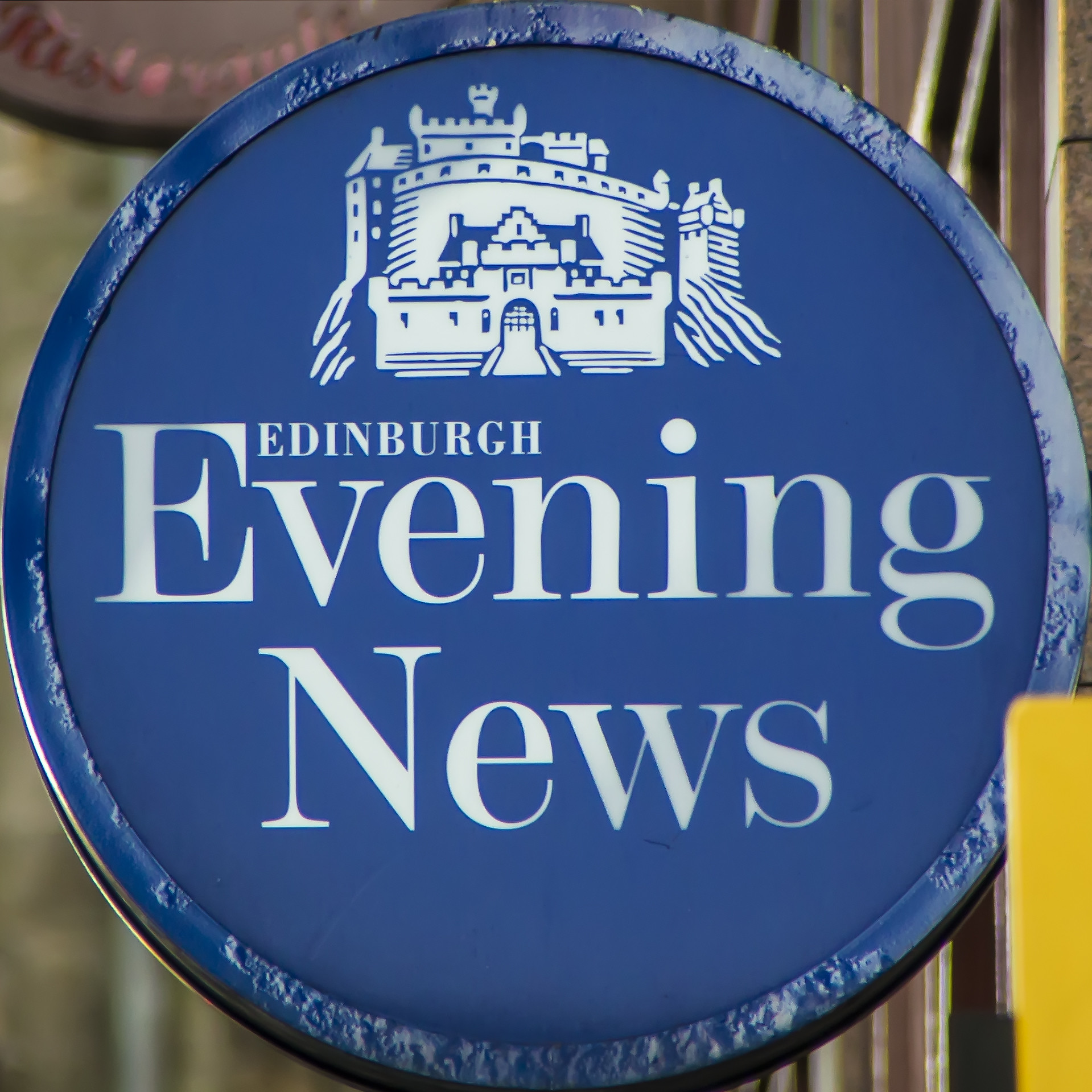A circular blue sign containing the words Edinburgh Evening News