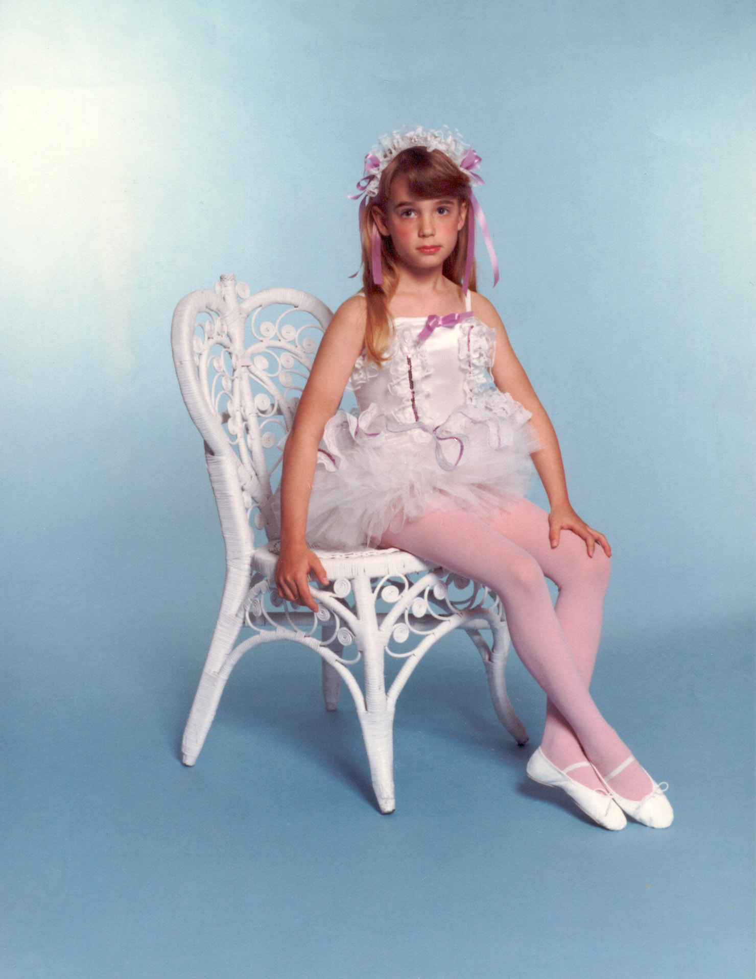 professional portrait of young ballerina sitting and pouting at the camera