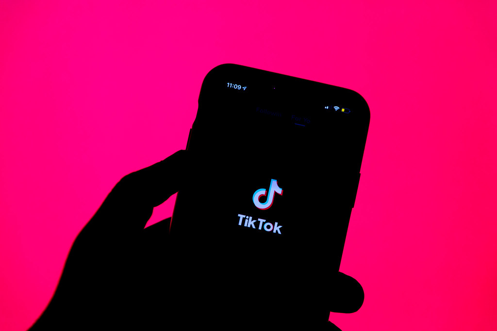 iPhone opening Tik Tok on a pink background