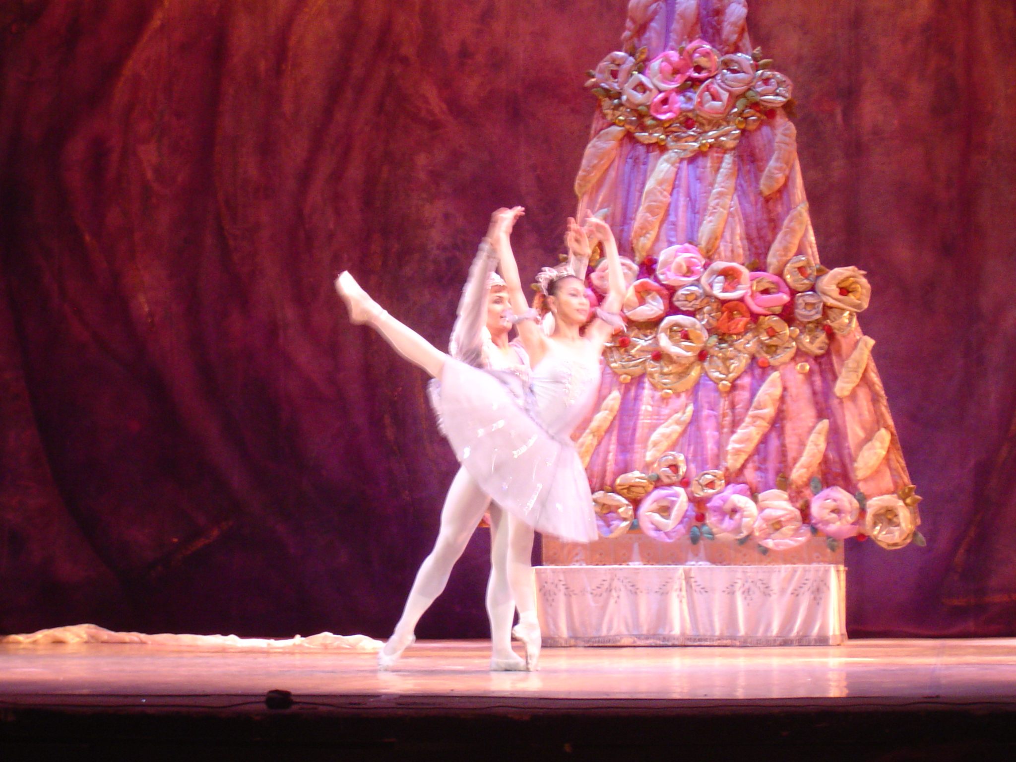 two ballet dancers on stage in front of a large prop cake