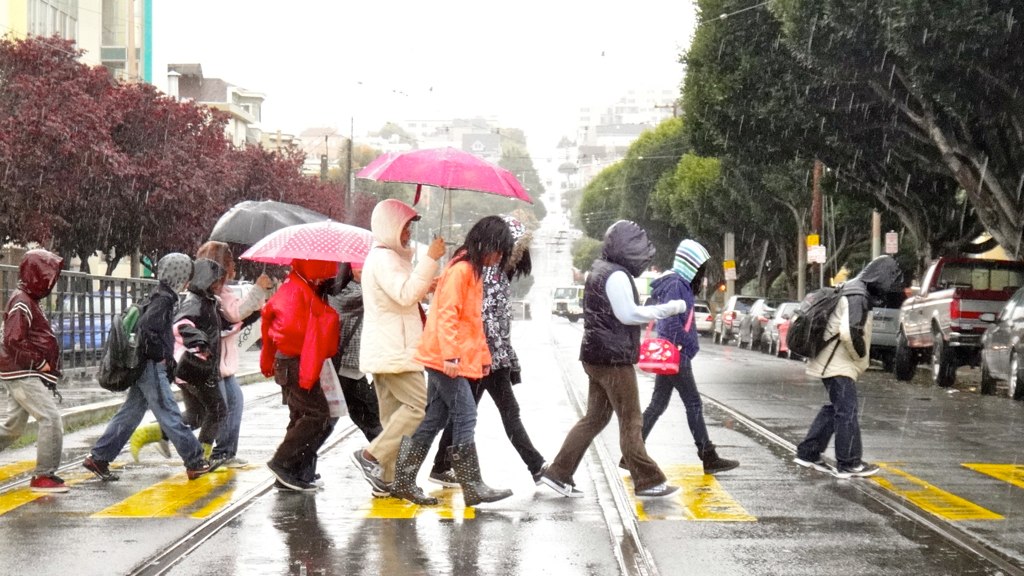 School children crossing road in the rain