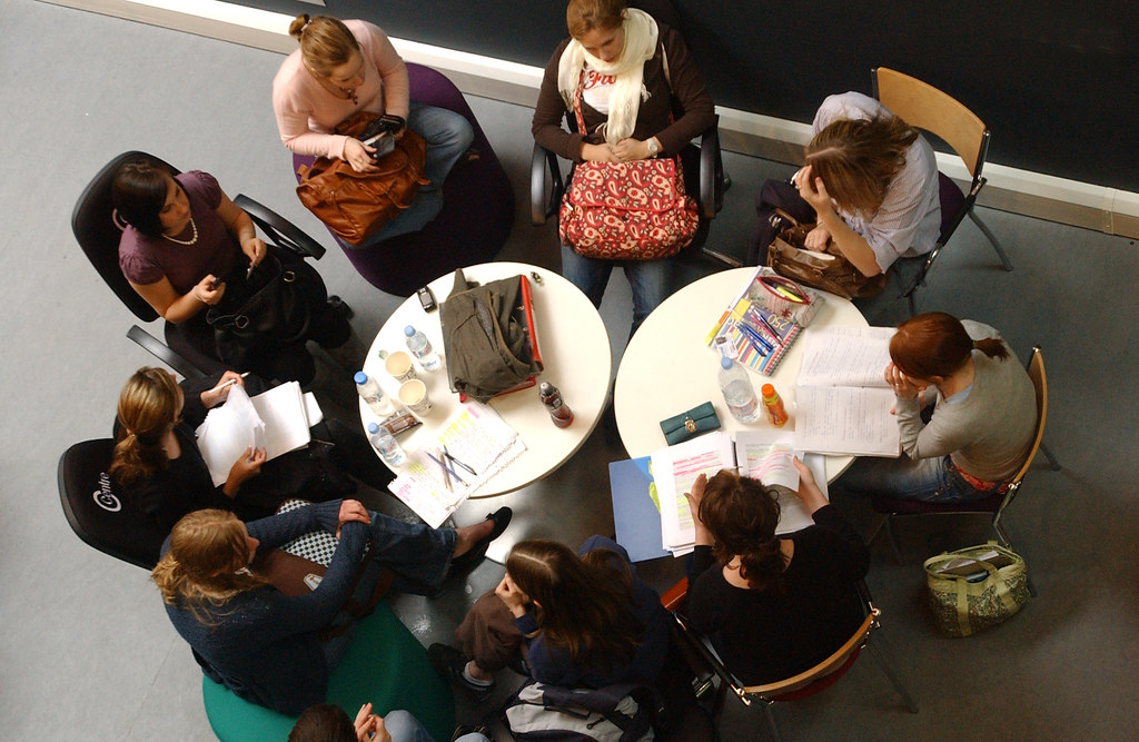 An overhead image of a group of uni students studying around two round tables